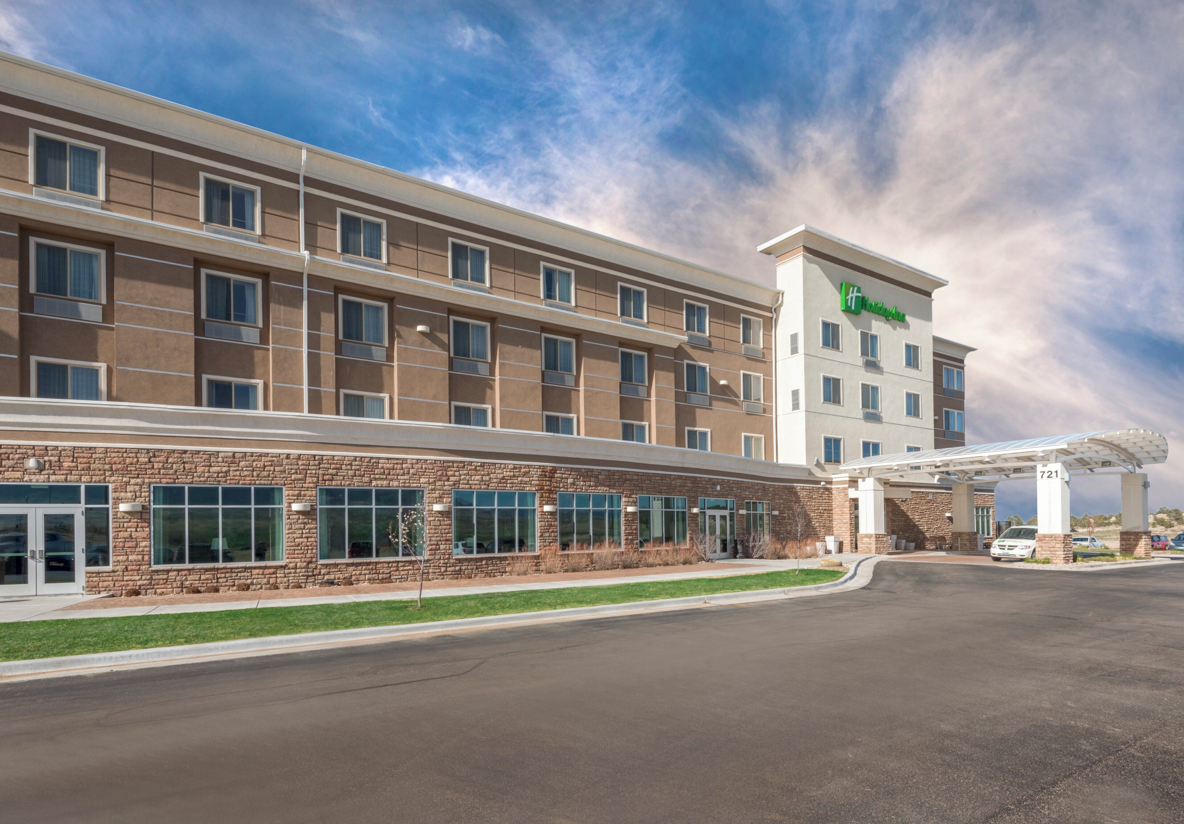 A modern hotel with a brick facade, multiple windows, and a covered parking area.