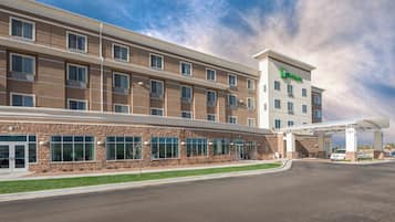 A modern hotel with a brick facade, multiple windows, and a covered parking area.