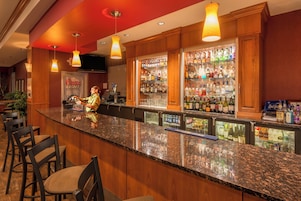 A bar area with a bartender, a variety of liquor bottles, and seating.