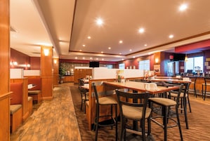 A restaurant with booths and tables, wooden flooring, and a bar area.