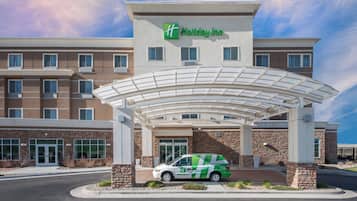 Un hotel Holiday Inn con entrada techada, zona de estacionamiento y servicio de transporte lanzadera verde.