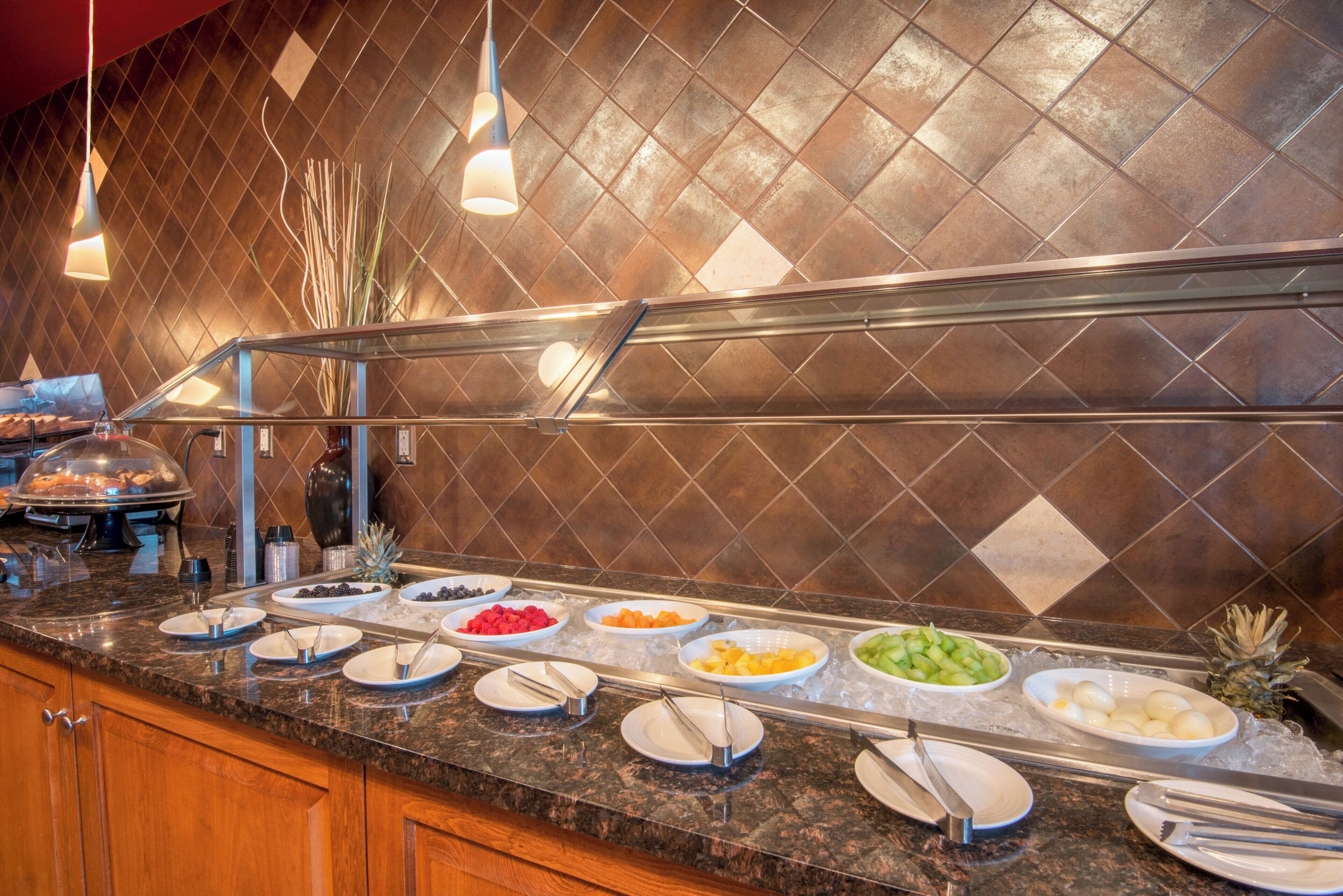 A buffet setup with various food items and utensils on a marble countertop.