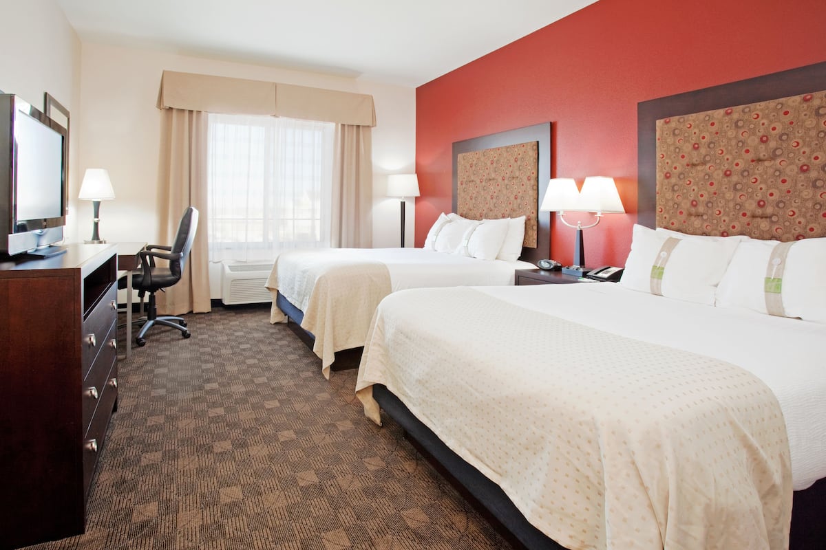 Quarto de hotel com duas camas, uma escrivaninha com um computador e uma cadeira.