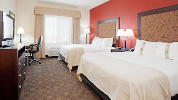 A hotel room with two beds, a desk with a computer, and a chair.