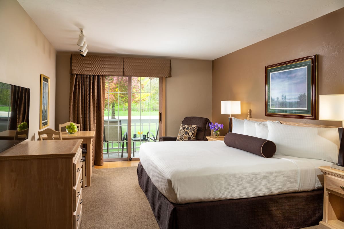 A hotel room with a large bed, a desk with a chair, a TV, and a window with curtains.