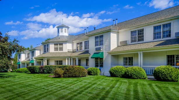 A row of white buildings with a central tower, green awnings, and well-maintained lawns. - The Ashbrooke (Egg Harbor)