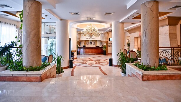 A hotel lobby with marble columns, a reception desk, and a chandelier. - Swiss Inn Nile Hotel (Giza)