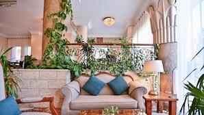 A cozy lobby with a sofa, chairs, a coffee table, and lush greenery. - Swiss Inn Nile Hotel (Giza)