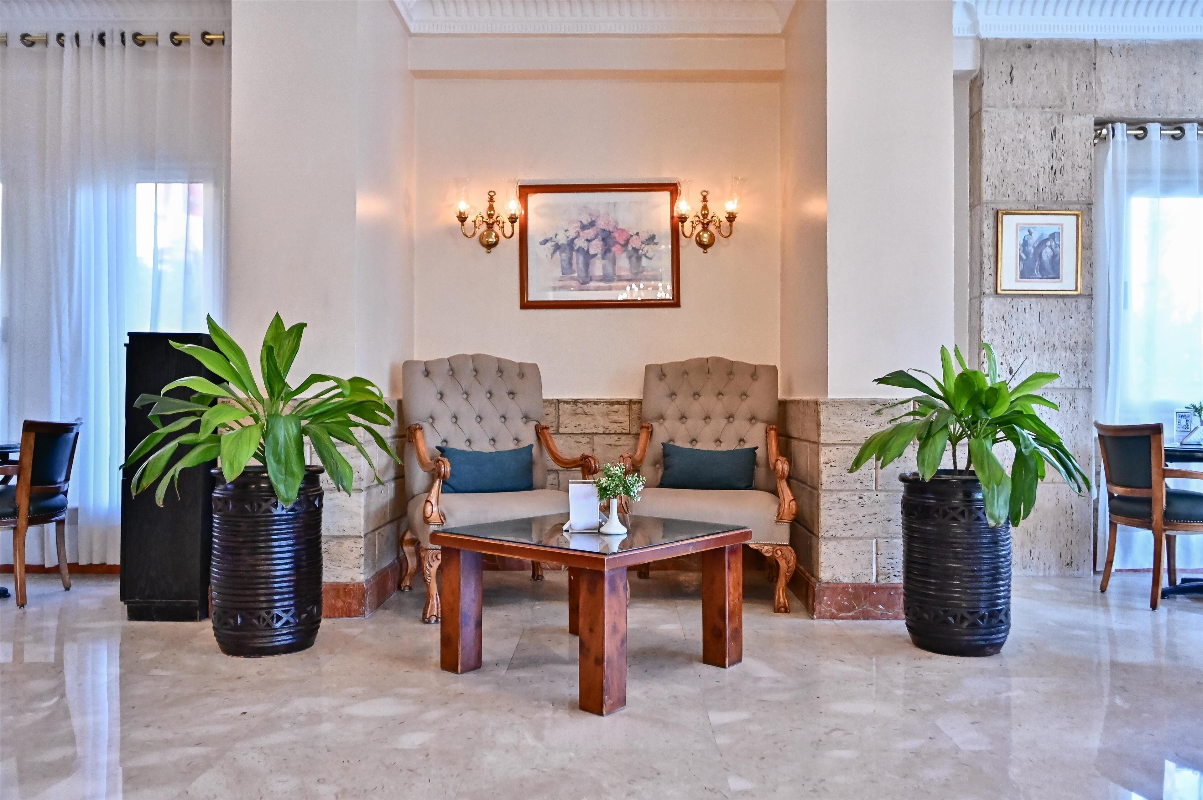 A lobby with two armchairs, a coffee table, and potted plants.