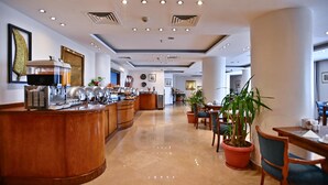 A hotel lobby with a buffet area, seating arrangements, and a reception desk. - Swiss Inn Nile Hotel (Giza)