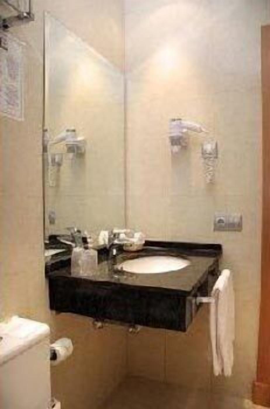 A bathroom with a sink, mirror, towel rack, and toilet.