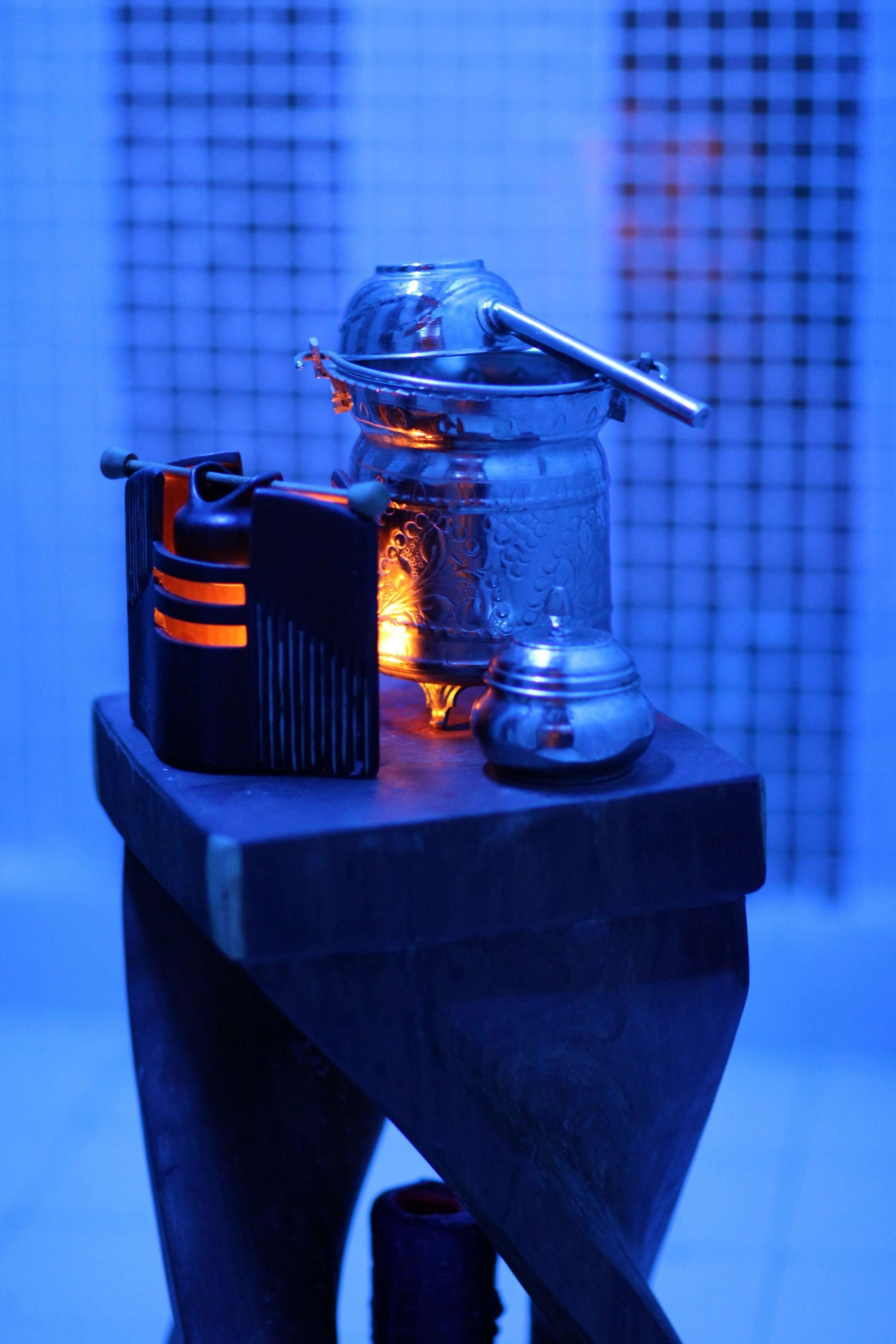 A table with a lantern, a lighter, and a metal container.