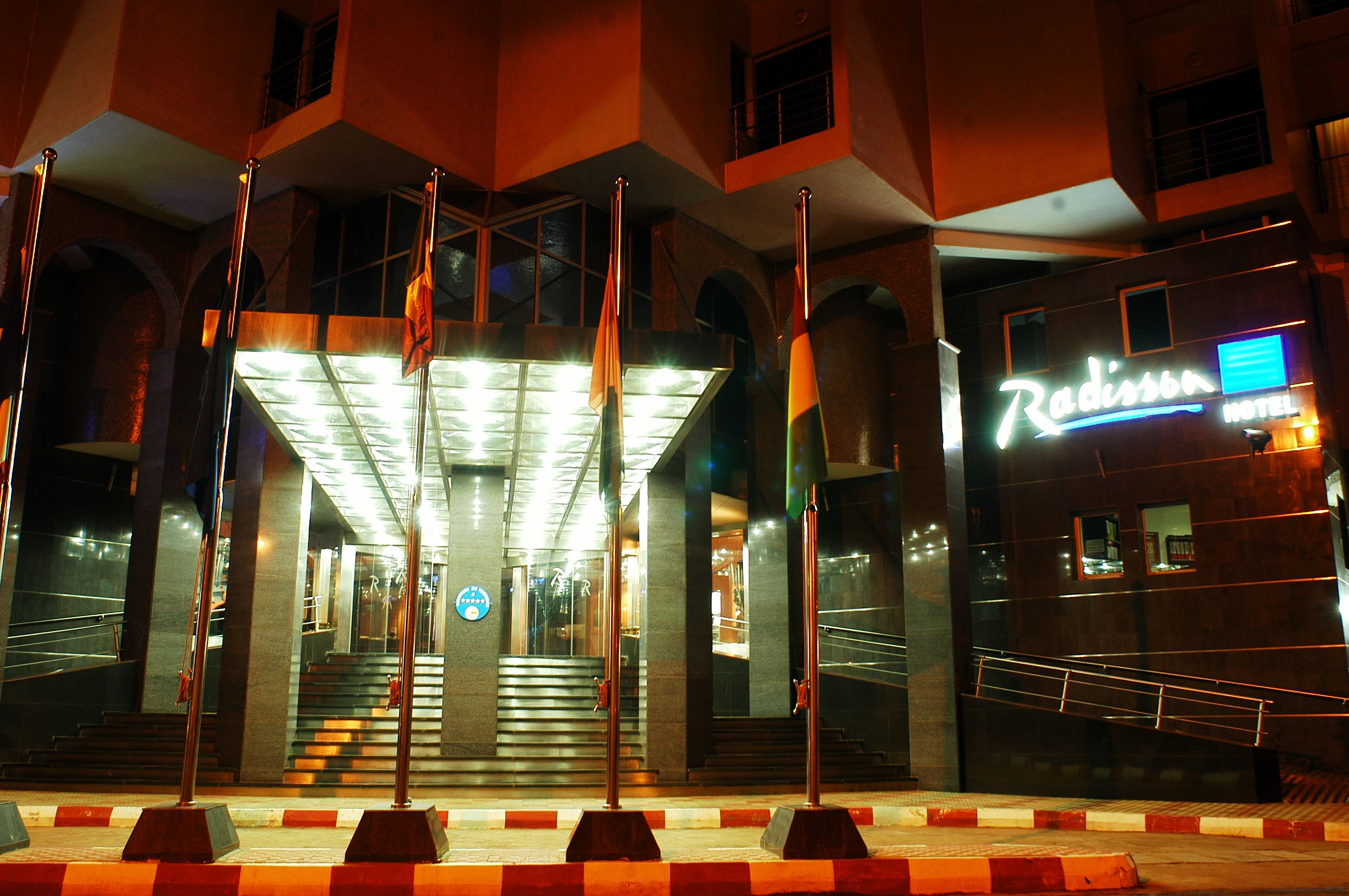 A hotel entrance with a staircase leading to the lobby, a neon sign, and a glass facade.