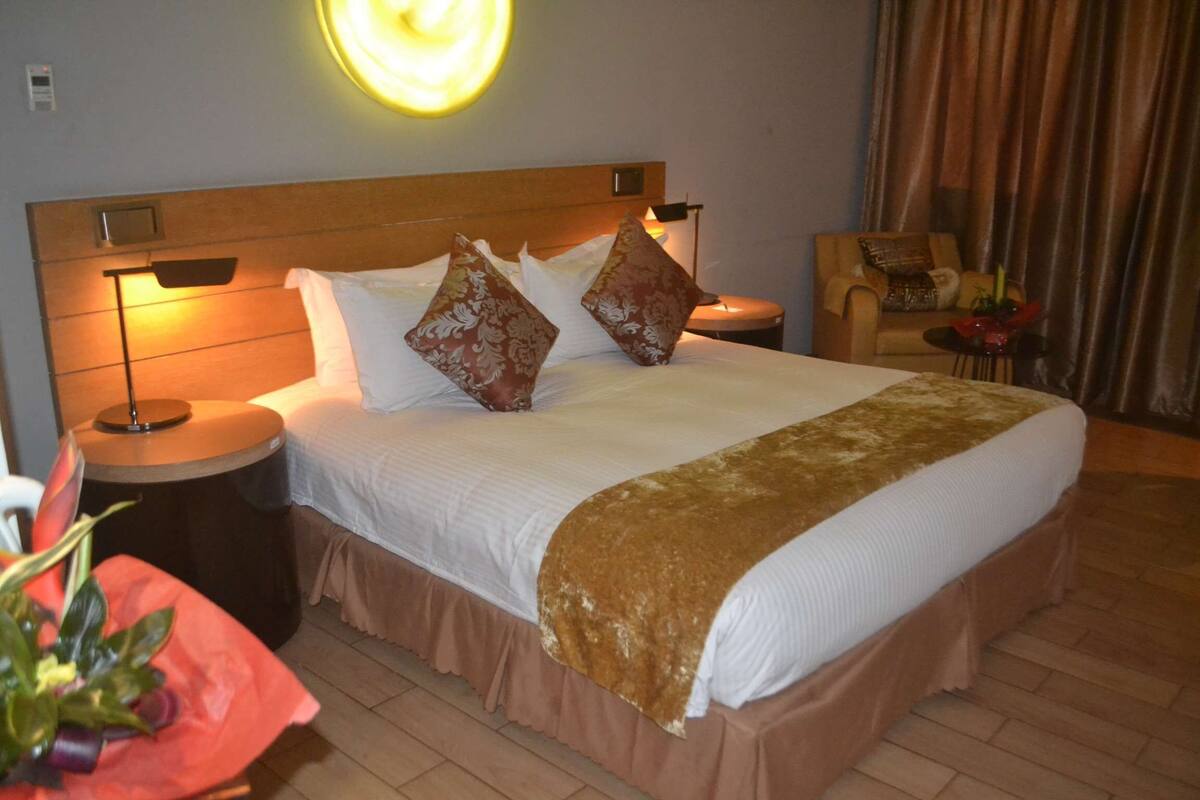 Ein Hotelzimmer mit einem großen Bett, einem Nachttisch, einem Beistelltisch, einem Stuhl und einer Wandleuchte.