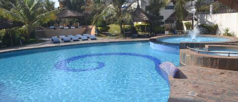 A swimming pool with lounge chairs and a small waterfall feature.