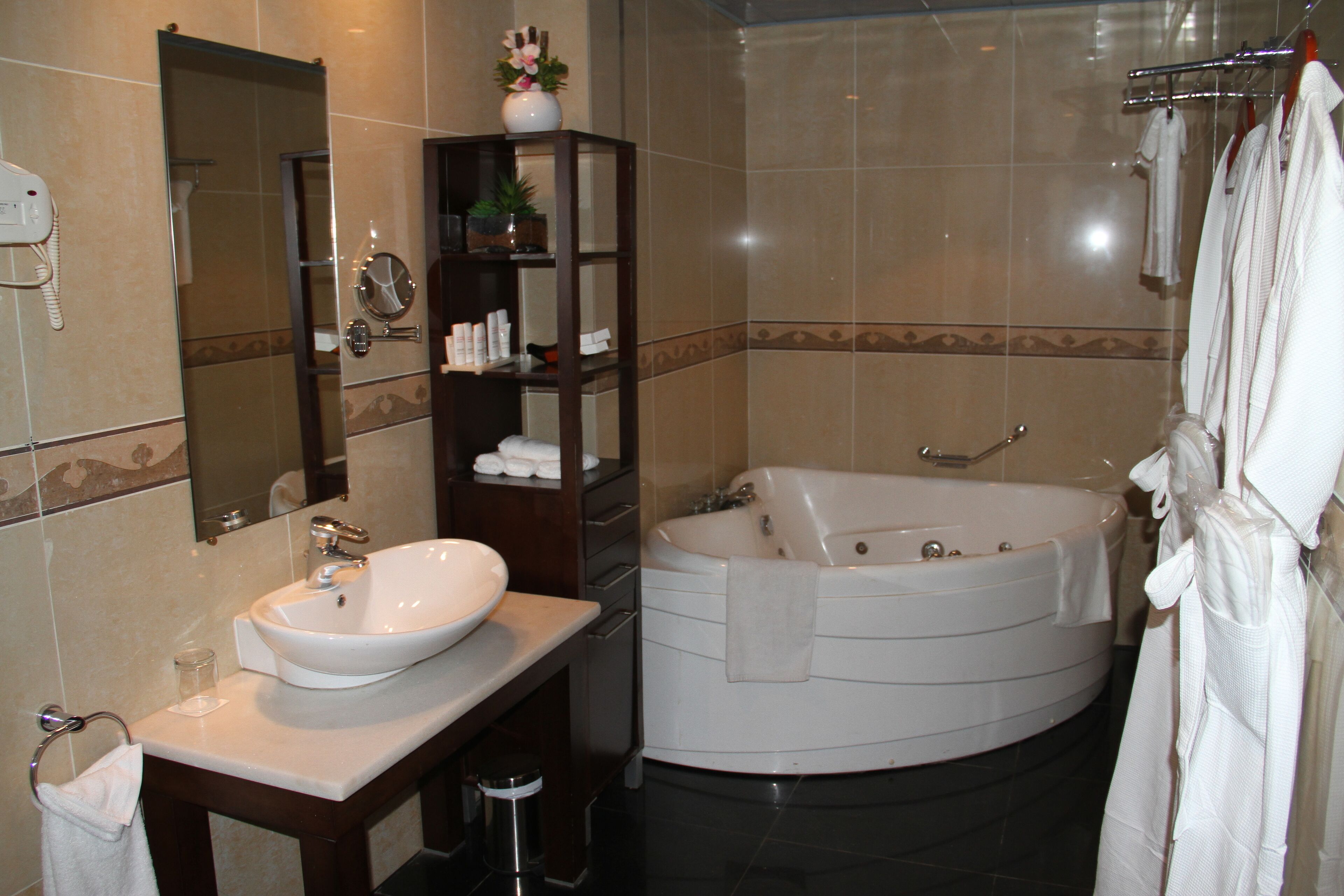 Un baño con lavamanos, espejo, toallero y bañera.