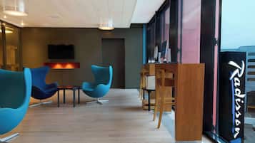 Interior moderno com cadeiras azuis, um balcão de recepção de madeira e uma janela grande com o nome 'Radisson'.