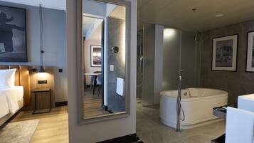 A modern hotel bathroom with a large mirror, a bathtub, and a shower area.
