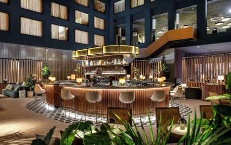 A modern bar area with a curved counter, bar stools, and a variety of seating options.