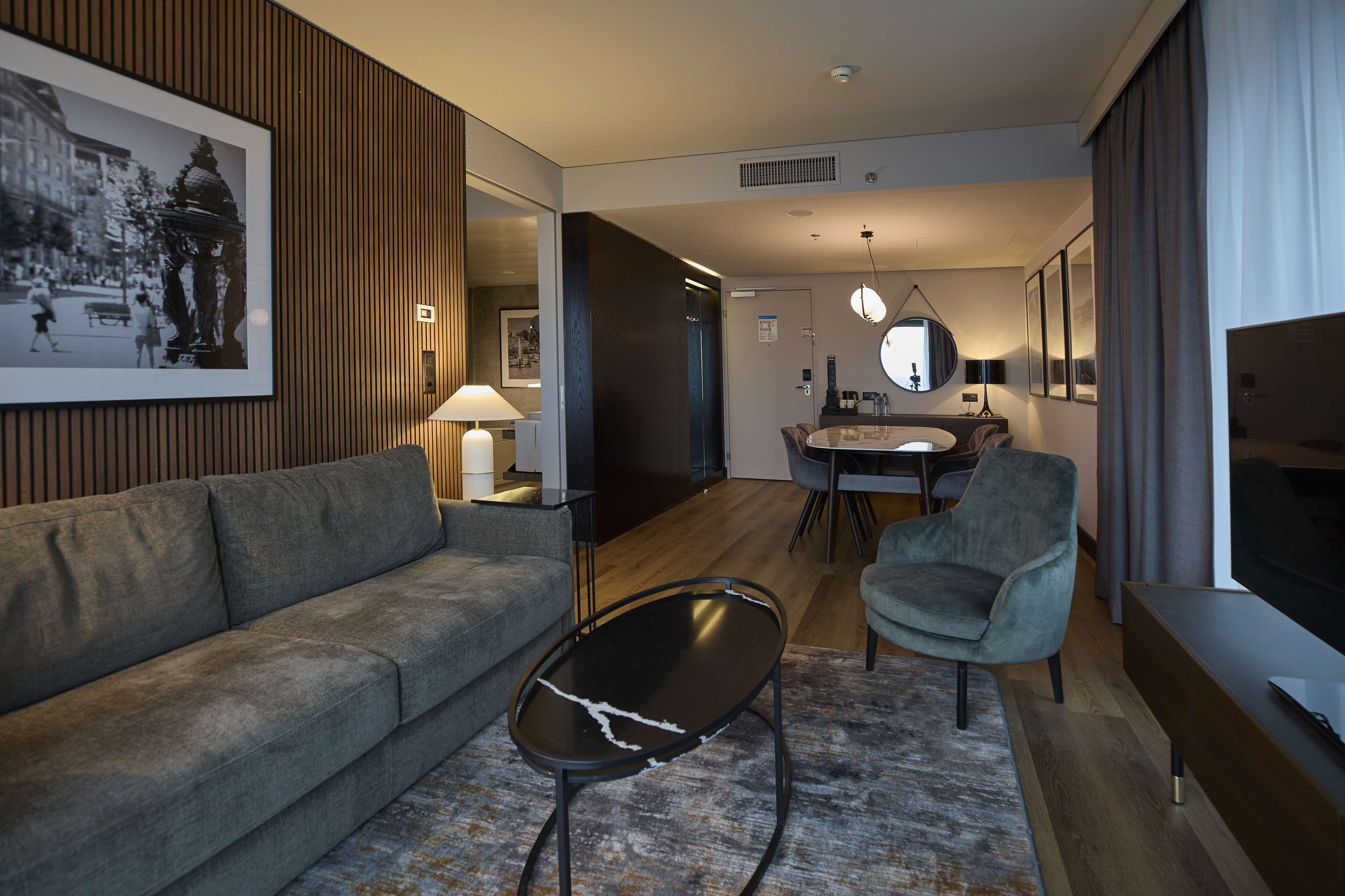 Una sala de estar moderna con un sofá, una mesa de centro, un televisor y un comedor con una mesa y sillas.