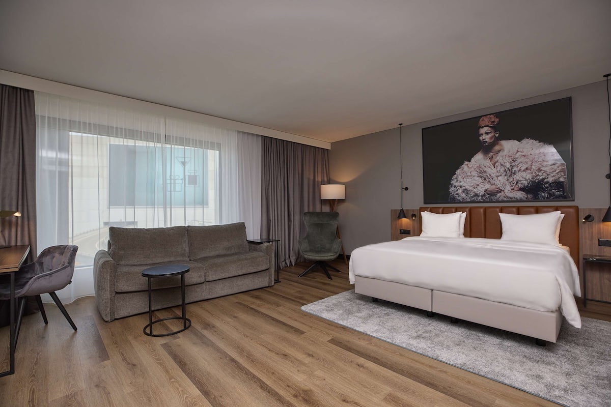 Una habitación de hotel moderna con una cama grande, un sofá, una silla y un escritorio.