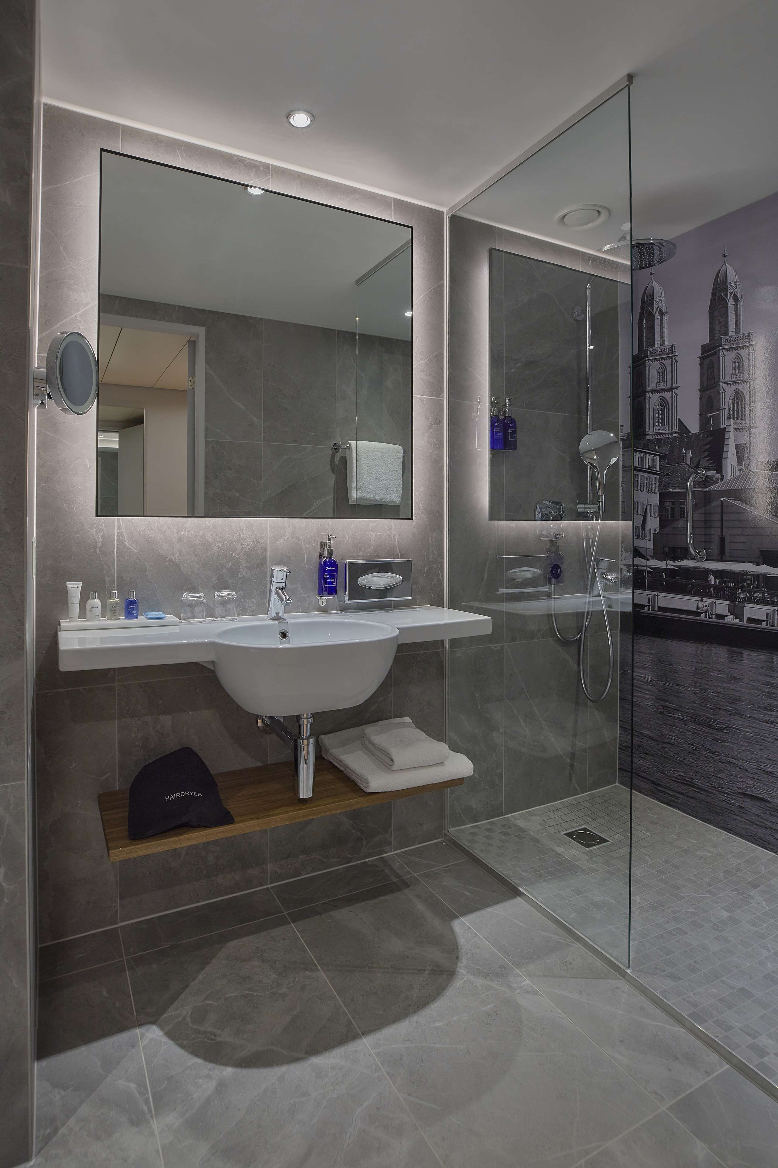 Ein modernes Badezimmer mit einem großen Spiegel, einem Waschbecken und einer Duschkabine.