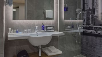 Ein modernes Badezimmer mit einem großen Spiegel, einem Waschbecken und einer Duschkabine.