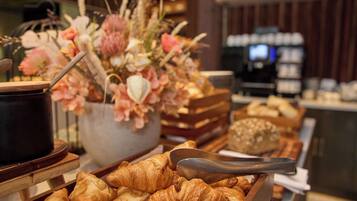 Un buffet avec des croissants et une composition florale en guise de décoration centrale.