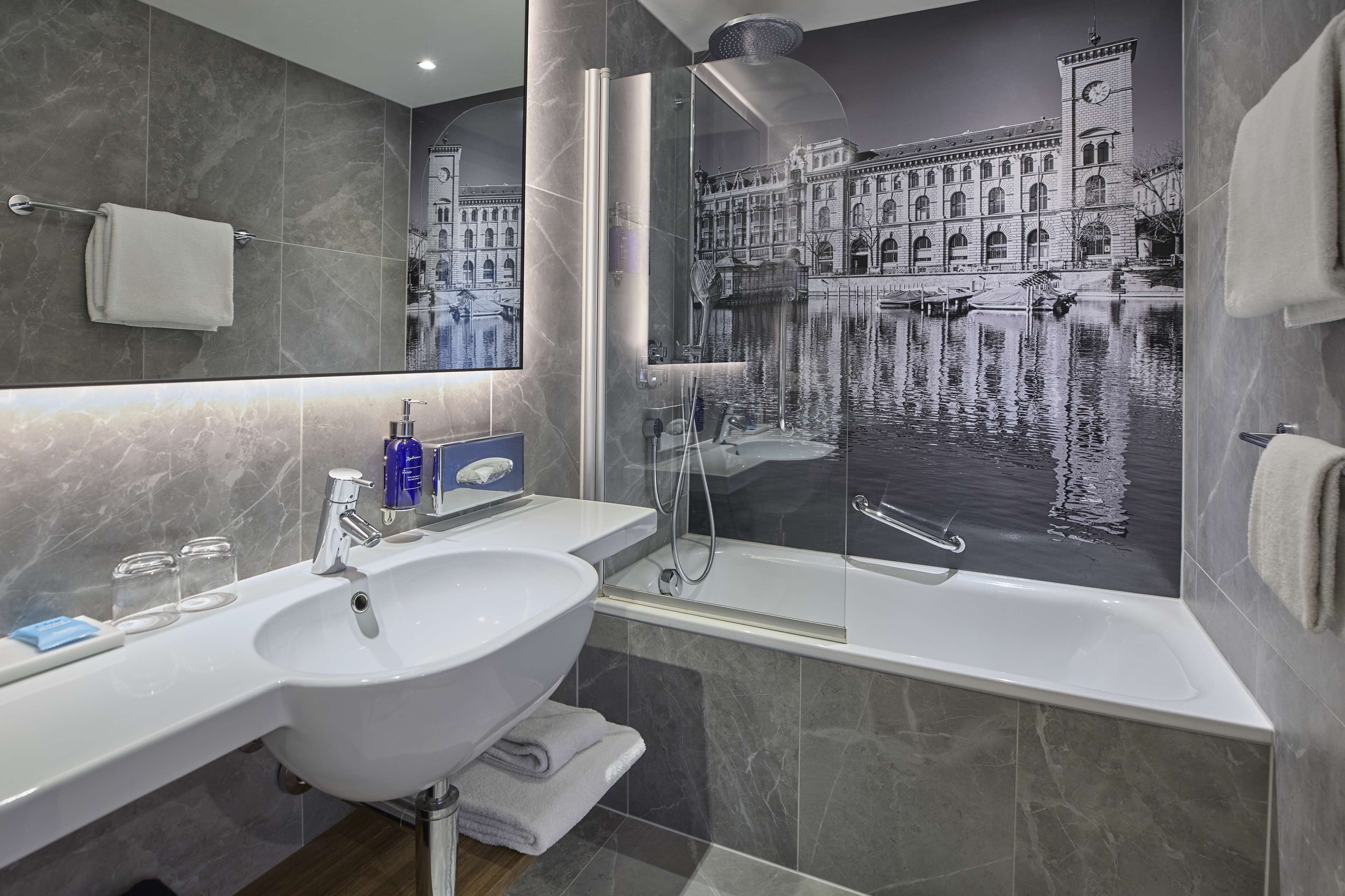A modern bathroom with a large sink, mirror, and a glass-enclosed shower.