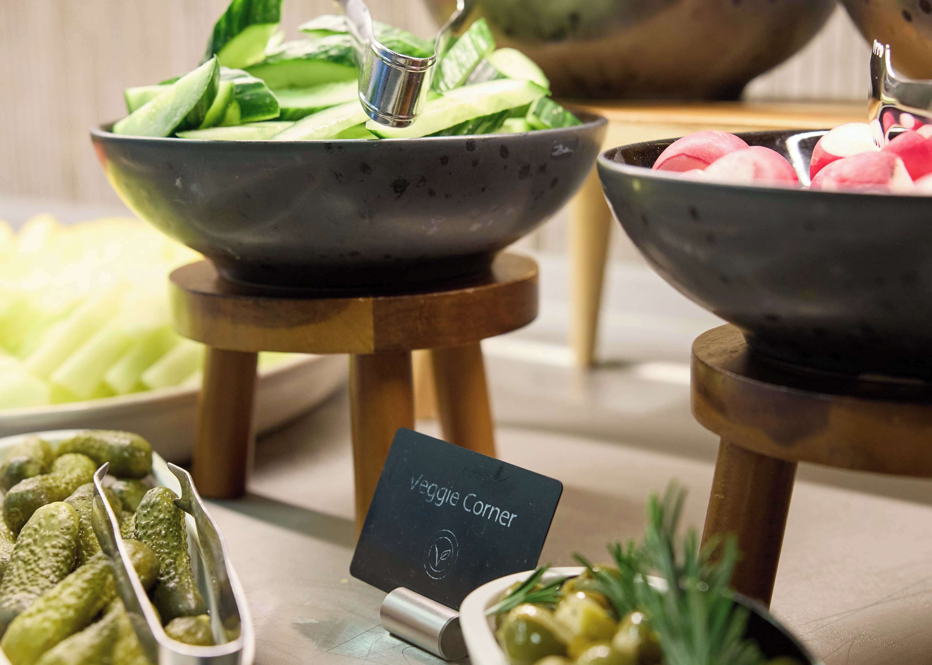 A buffet with various vegetable options including cucumbers, radishes, and pickles.