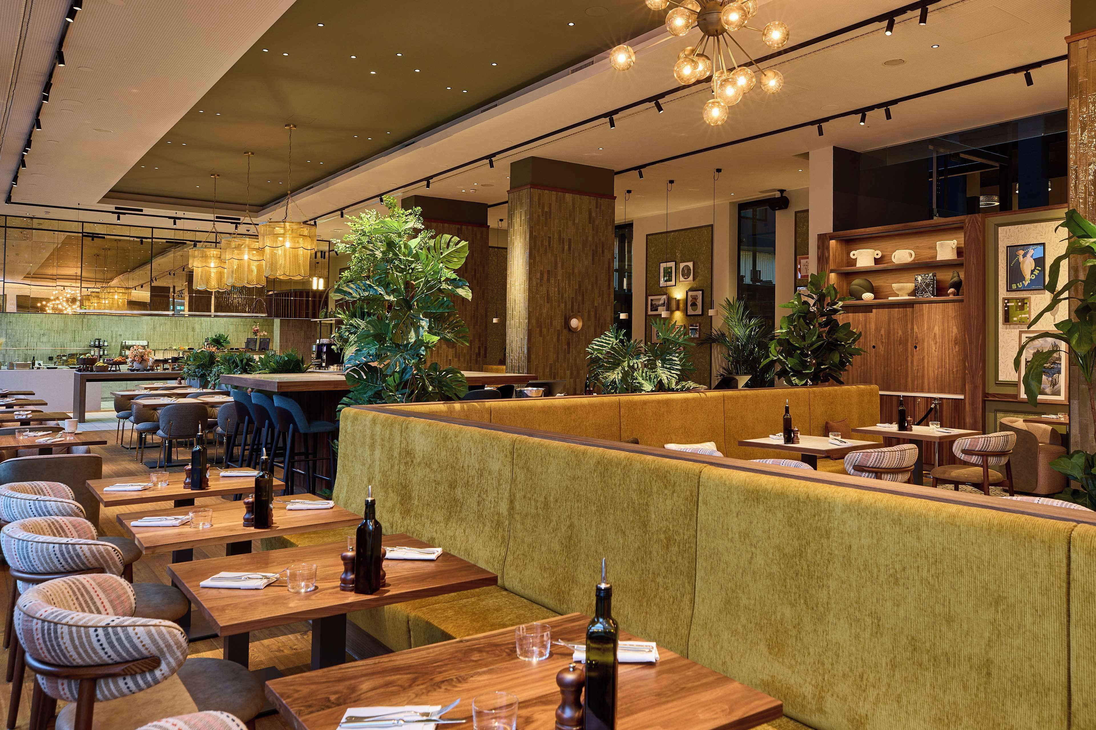 Een modern restaurant met houten tafels, zachte zittingen en hanglampen.
