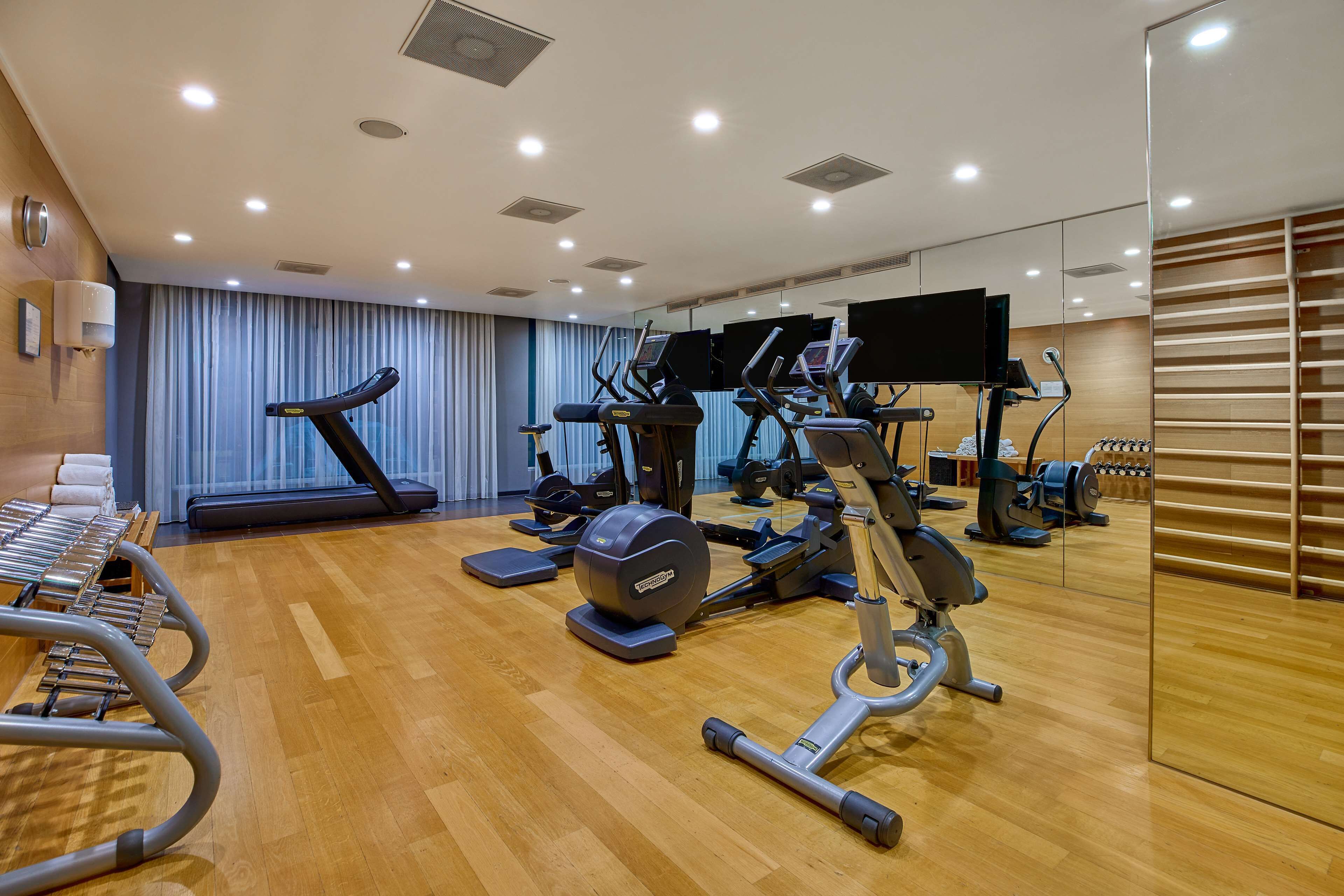 Uma academia com equipamentos de exercício, um espelho e piso de madeira.