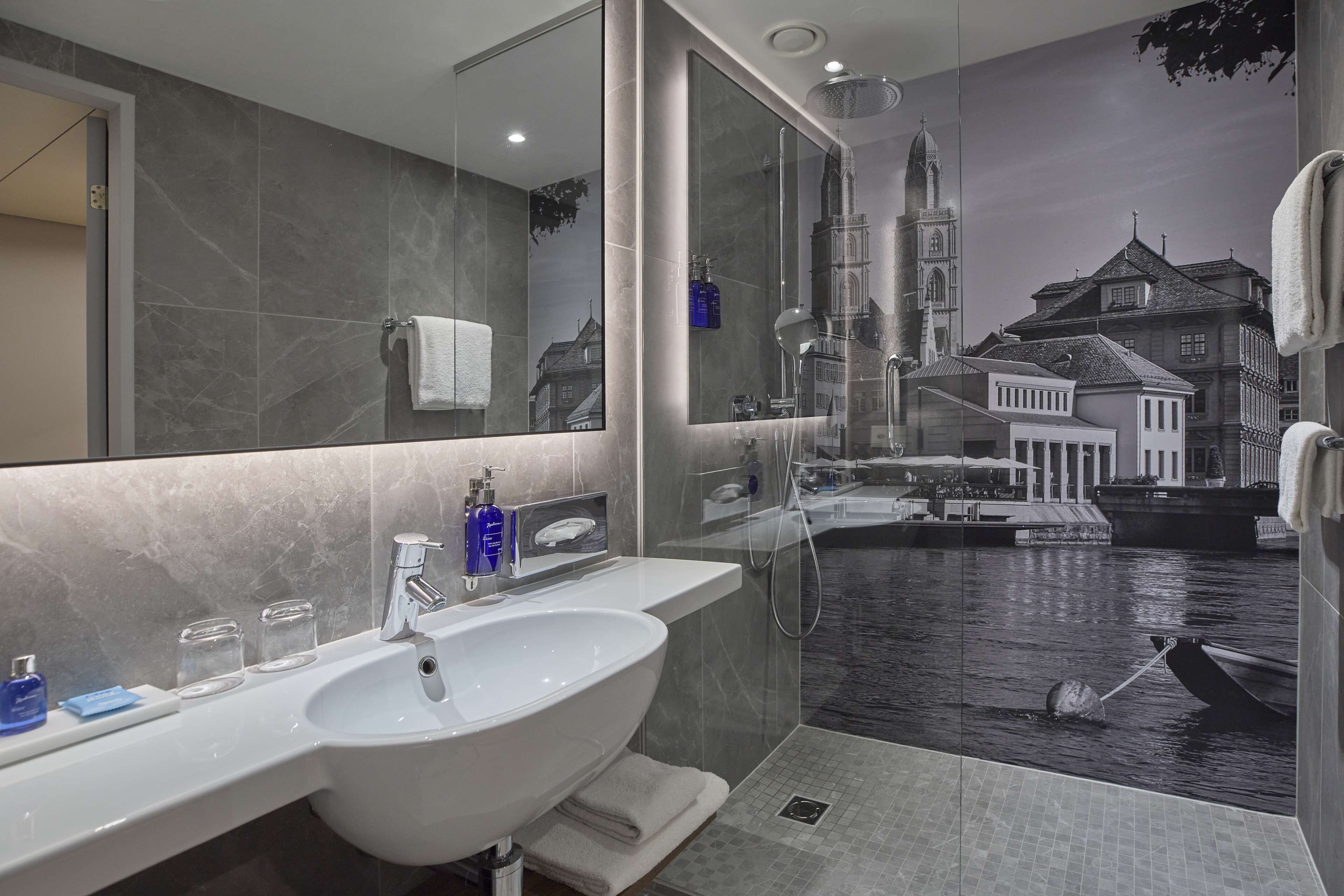 Un baño moderno con un espejo grande, un lavabo blanco y una zona de ducha.