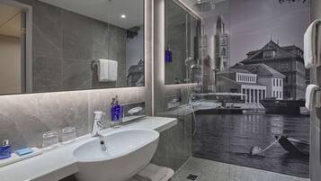 Un baño moderno con un espejo grande, un lavabo blanco y una zona de ducha.