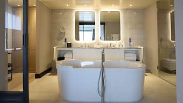 Un baño moderno con una bañera independiente grande, un lavamanos doble y dos espejos sobre los lavabos.
