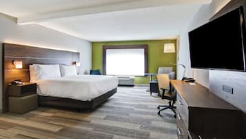 A hotel room with a bed, desk, chair, TV, and a window with a view.