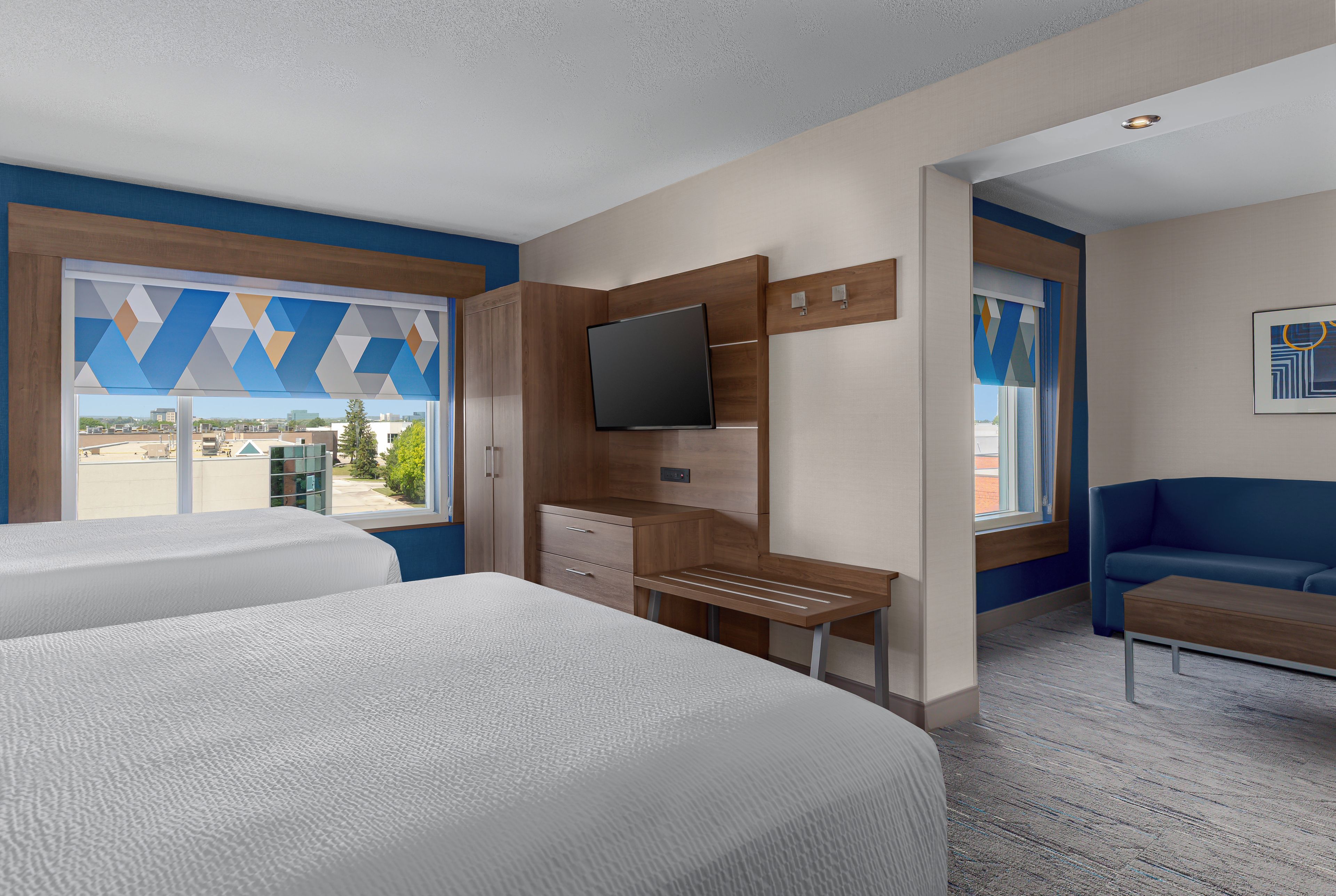 A hotel room with two beds, a TV, a desk, and a couch.