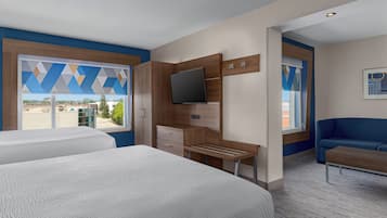 A hotel room with two beds, a TV, a desk, and a couch.