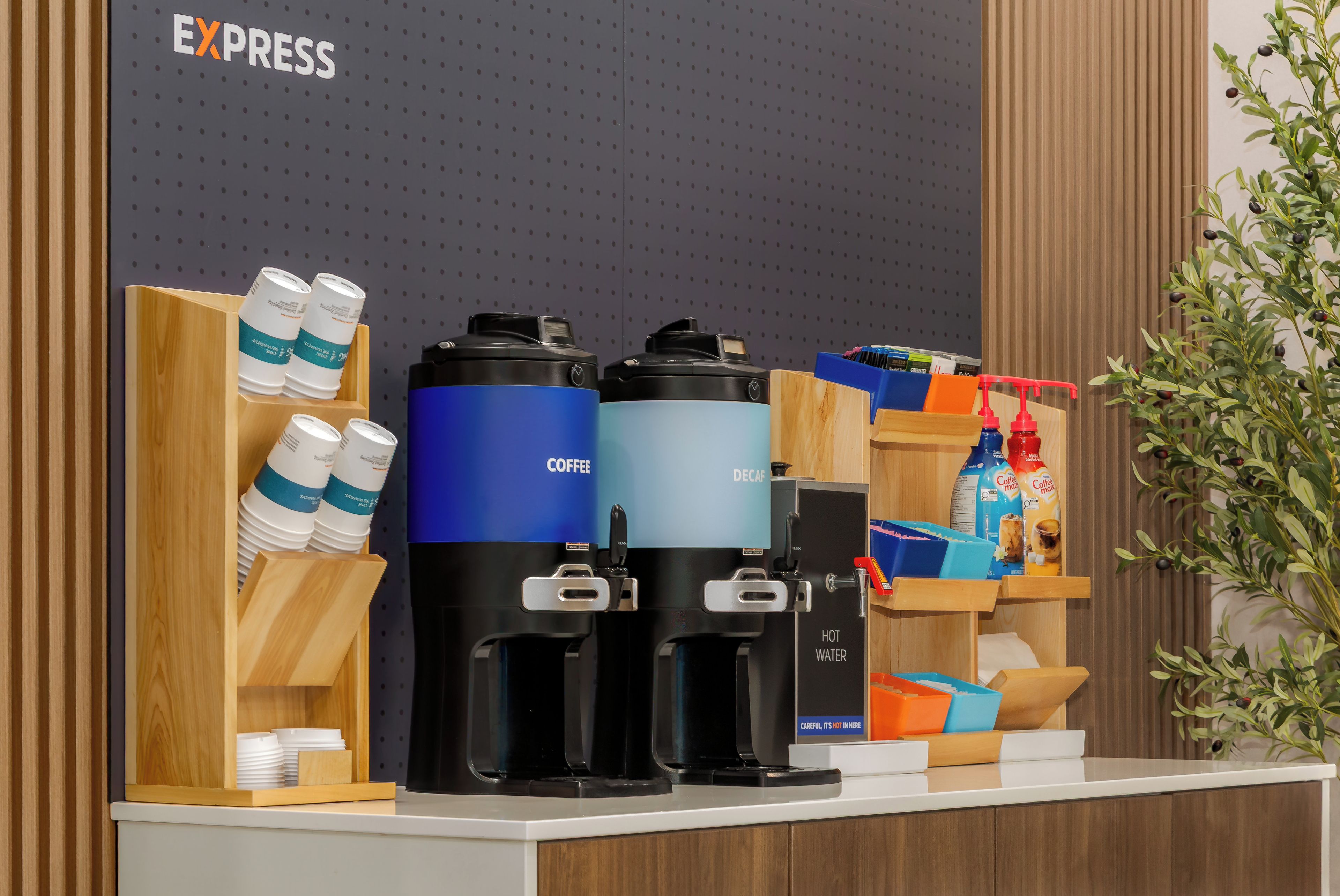 En kaffestation med to kaffemaskiner, en vanddispenser og forskellige kaffekapsler.