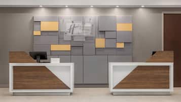 Zona de recepción con un cartel de Holiday Inn Express, dos mostradores de recepción y un diseño moderno de pared.