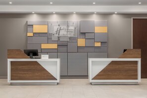 Un espace d’accueil avec un panneau « Holiday Inn Express », deux comptoirs de réception et un décor mural moderne.