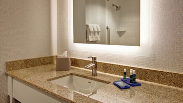 A bathroom with a granite countertop sink, a mirror, and a towel rack.