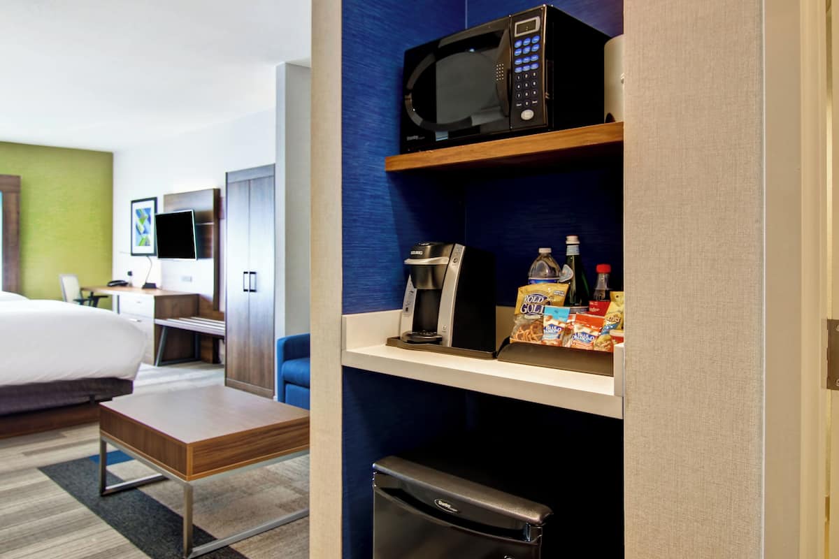Une chambre d’hôtel équipée d’un lit, d’un bureau, d’un four à micro-ondes, d’une machine à café et d’un mini-réfrigérateur.