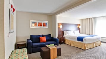 A hotel room with a sofa, a bed, a small table, and a wall-mounted picture.