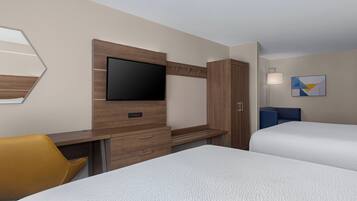 A hotel room with a bed, a desk with a flat-screen TV, a wardrobe, a chair, and a bedside table.
