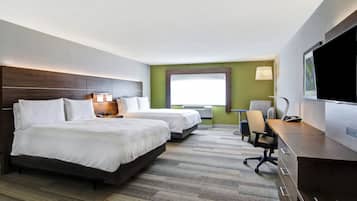 Une chambre d’hôtel avec deux lits, un bureau, une chaise, une télévision et une fenêtre avec des stores.