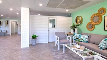 A spacious living area with a herringbone floor, a sofa set, a coffee table, and decorative wall art.