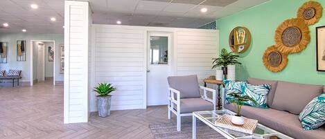 A spacious living area with a herringbone floor, a sofa set, a coffee table, and decorative wall art.