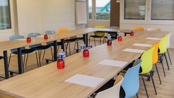 A conference room with a long table, colorful chairs, and water bottles.