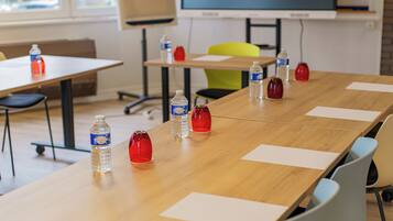 A conference room with a long table, chairs, water bottles, and a projector screen.
